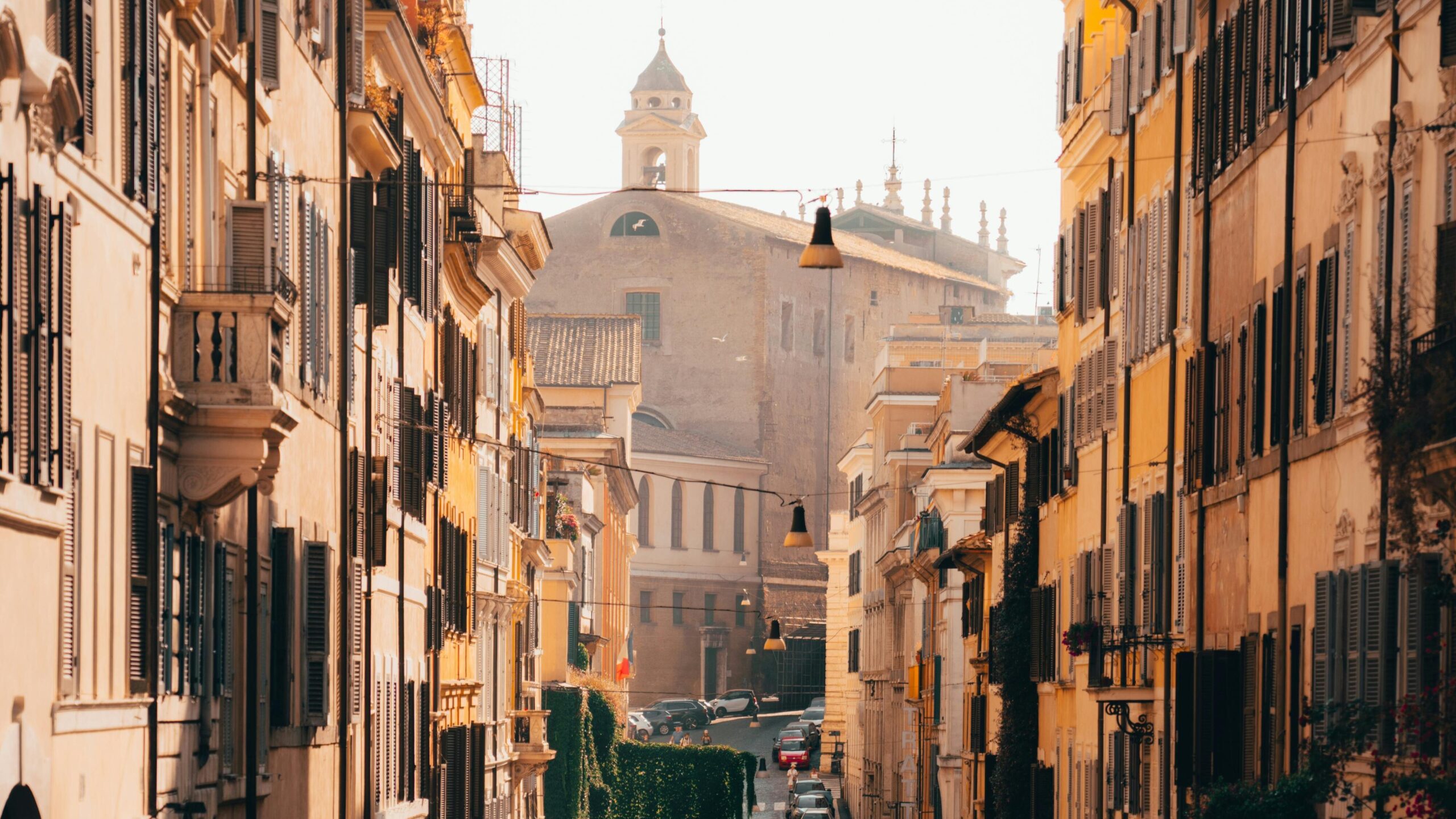 Picturesque street scene in Rome, Italy, showcasing historic architecture and a warm sunset glow.