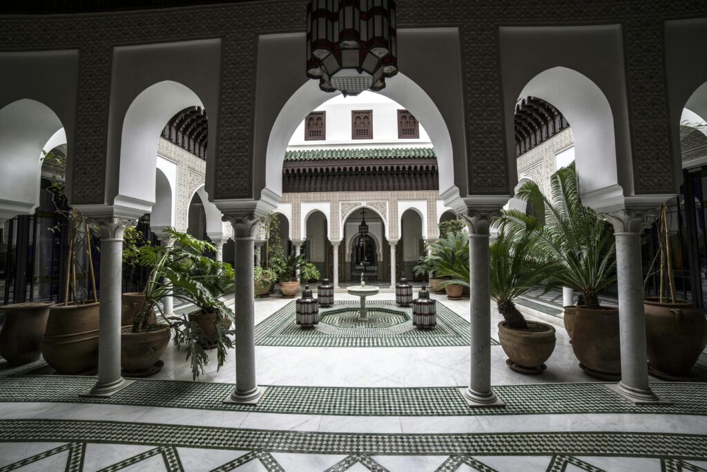 Beautiful oriental palace inner yard with arches and mosaic on floor decorated with lush potted plants and cozy fountain in center